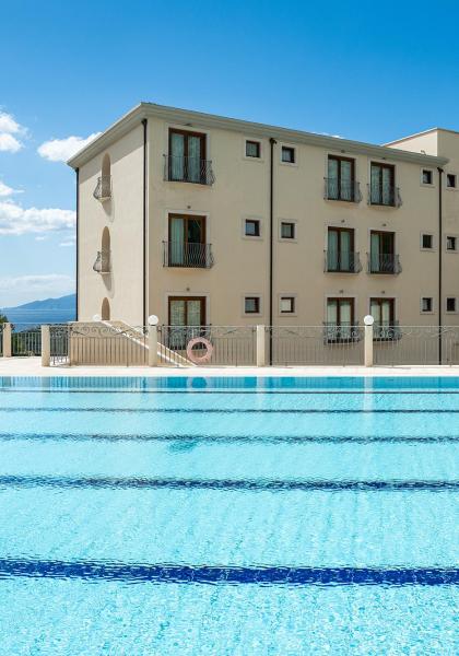 Hotel con piscina e vista mare, cielo sereno.