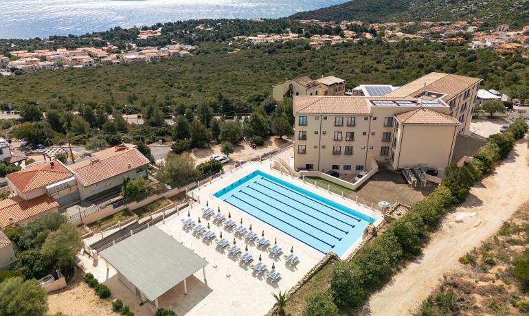 Panoramic view of pool, sea, and green hills.