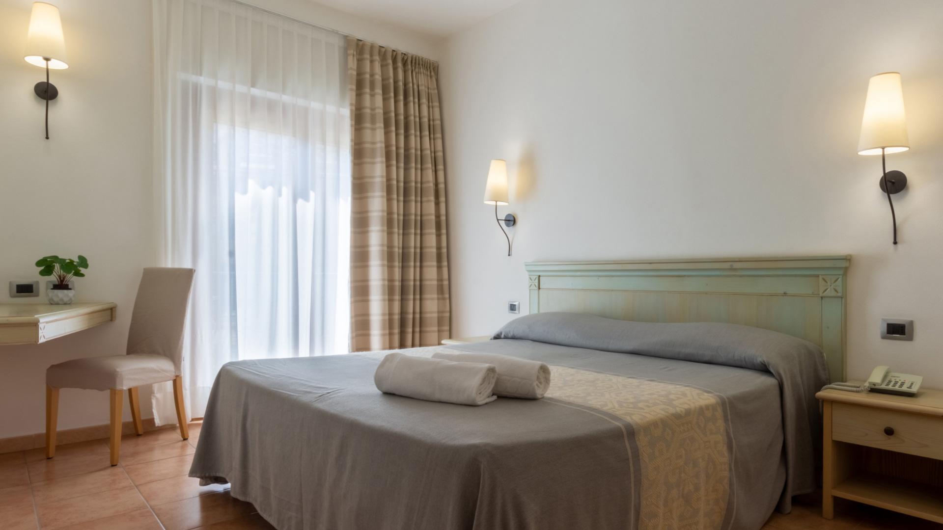 Camera accogliente con letto matrimoniale, luci soffuse e arredo elegante.