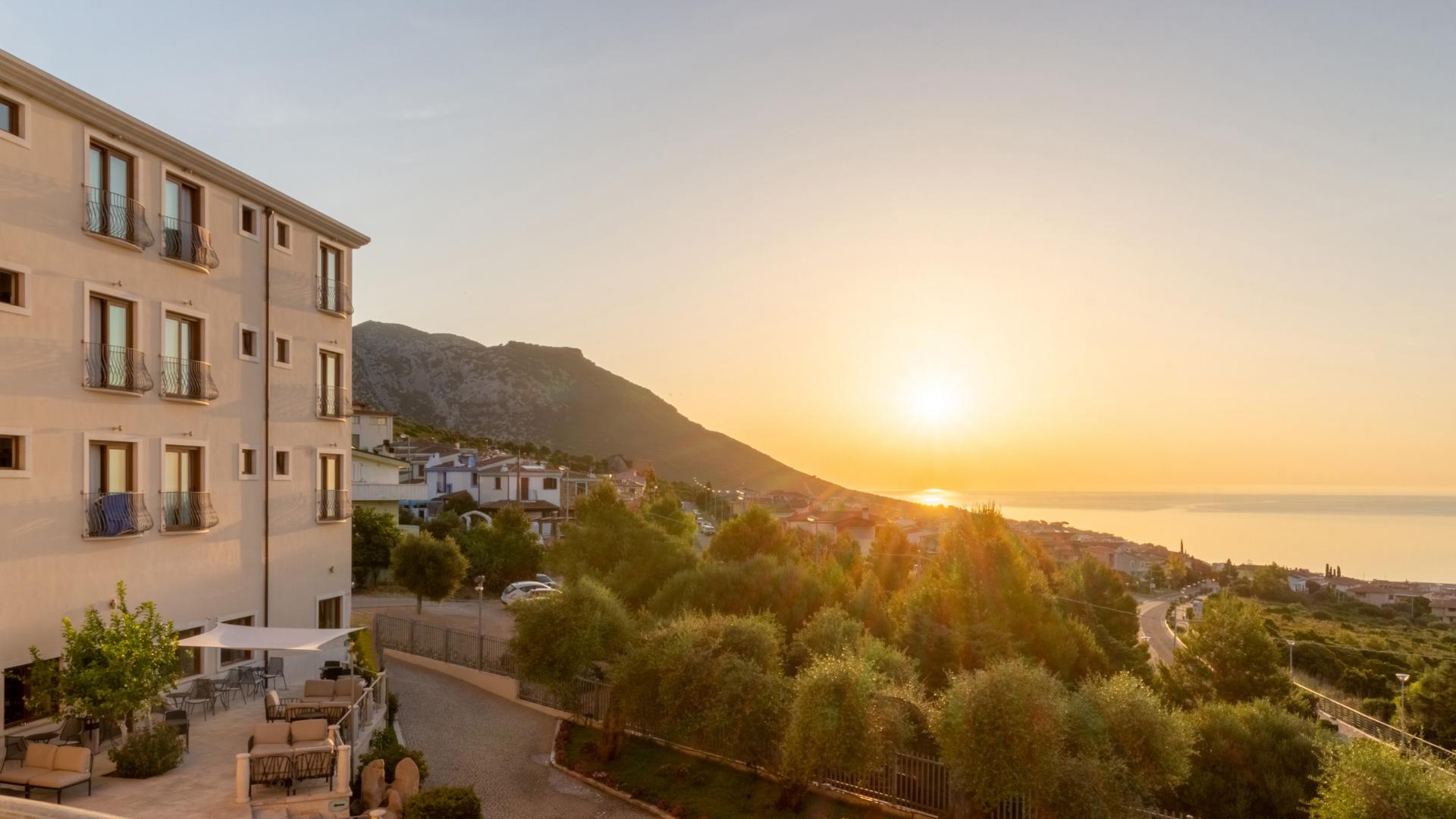 Tramonto dorato su colline e mare, atmosfera serena e calda.